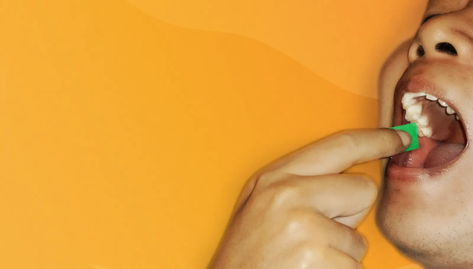 Image of an open STIM Frost Mint foil packaging and a man placing a STIM strip on his inner cheek