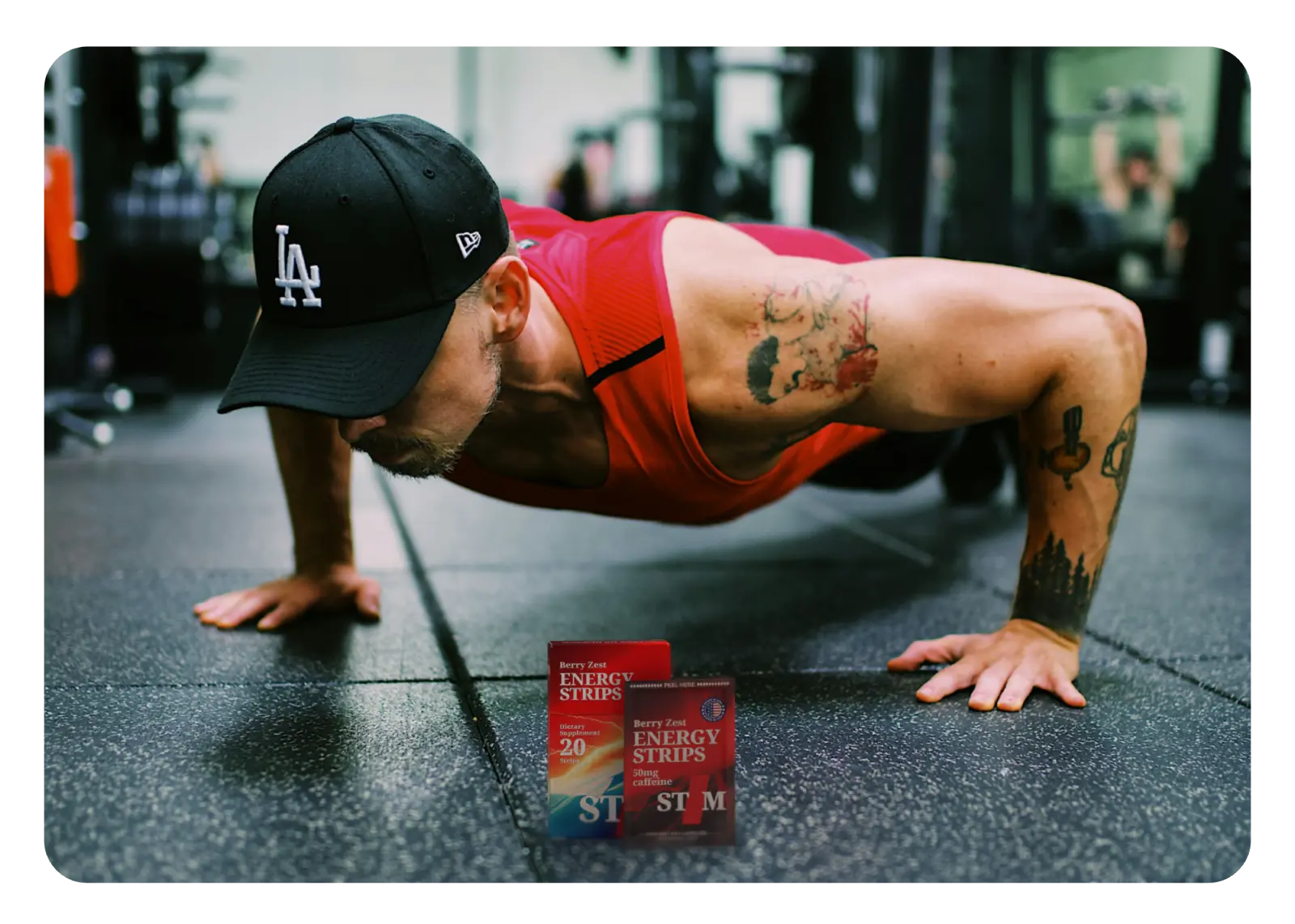 Image of STIM Berry Zest pack and strip in a gym with a guy doing pushups in the background